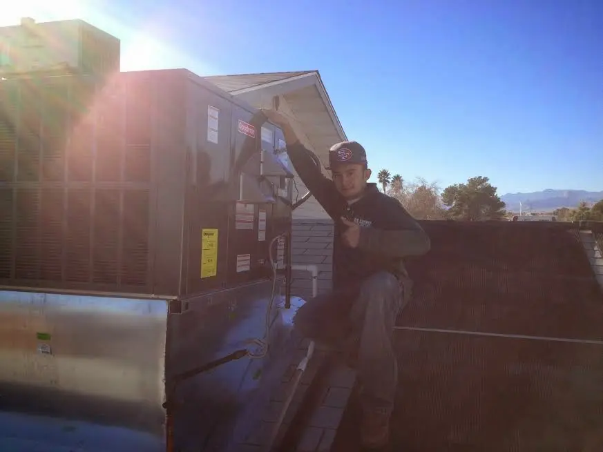 HVAC technician performing AC Tune-Up on a rooftop unit in Mead